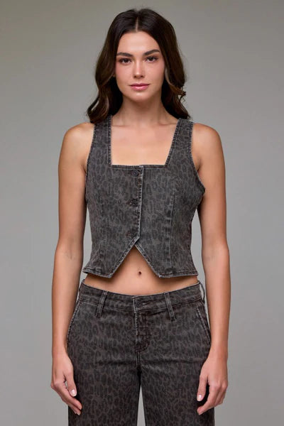 Woman wearing a denim vest and pants against a gray background